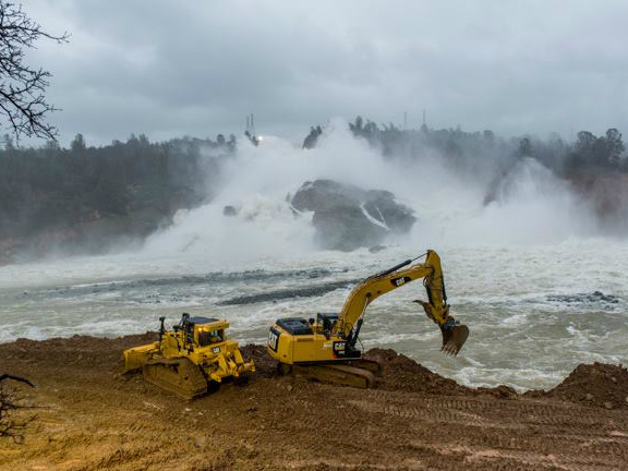 Heavy equipment operators dig access points to the river below Oroville Dam to allow access to remove the sediment at the base of the spillway on February 17, 2017.